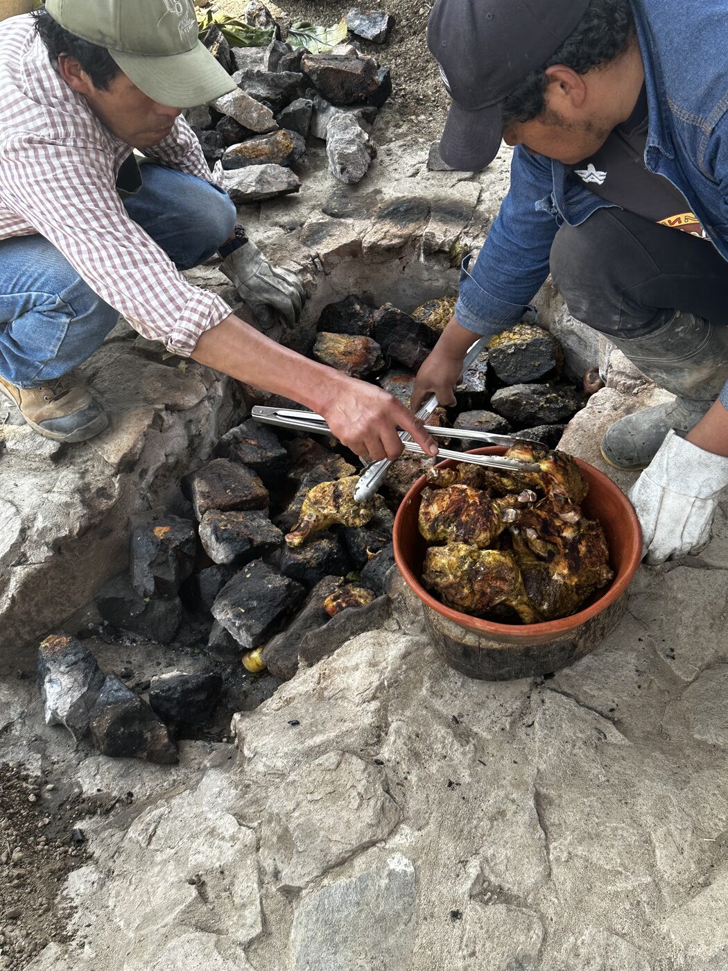 Hands preparing a traditional pachamanca, an Andean earth oven